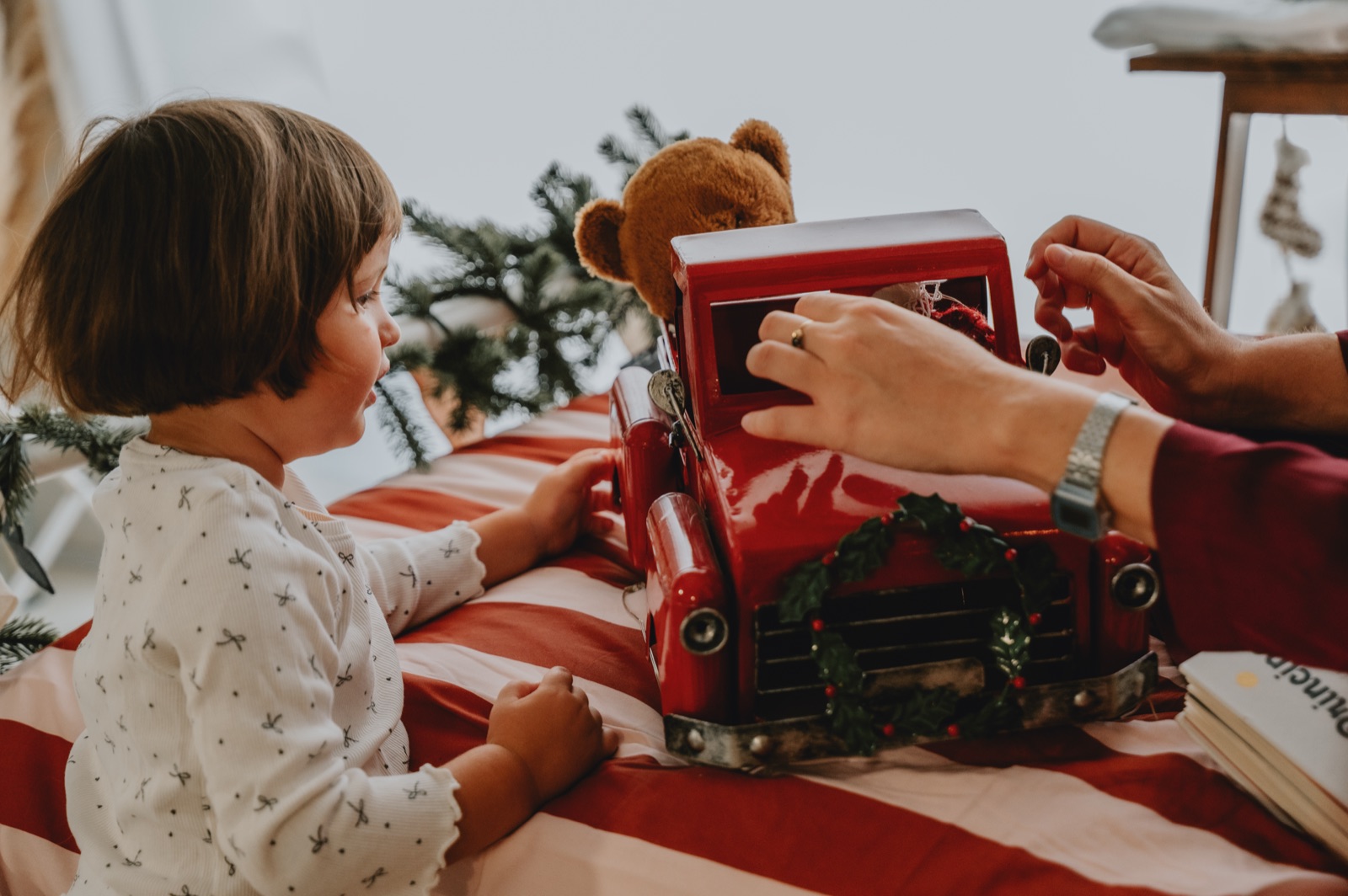 Le mani di un adulto che aprono il camioncino rosso insieme alla bambina