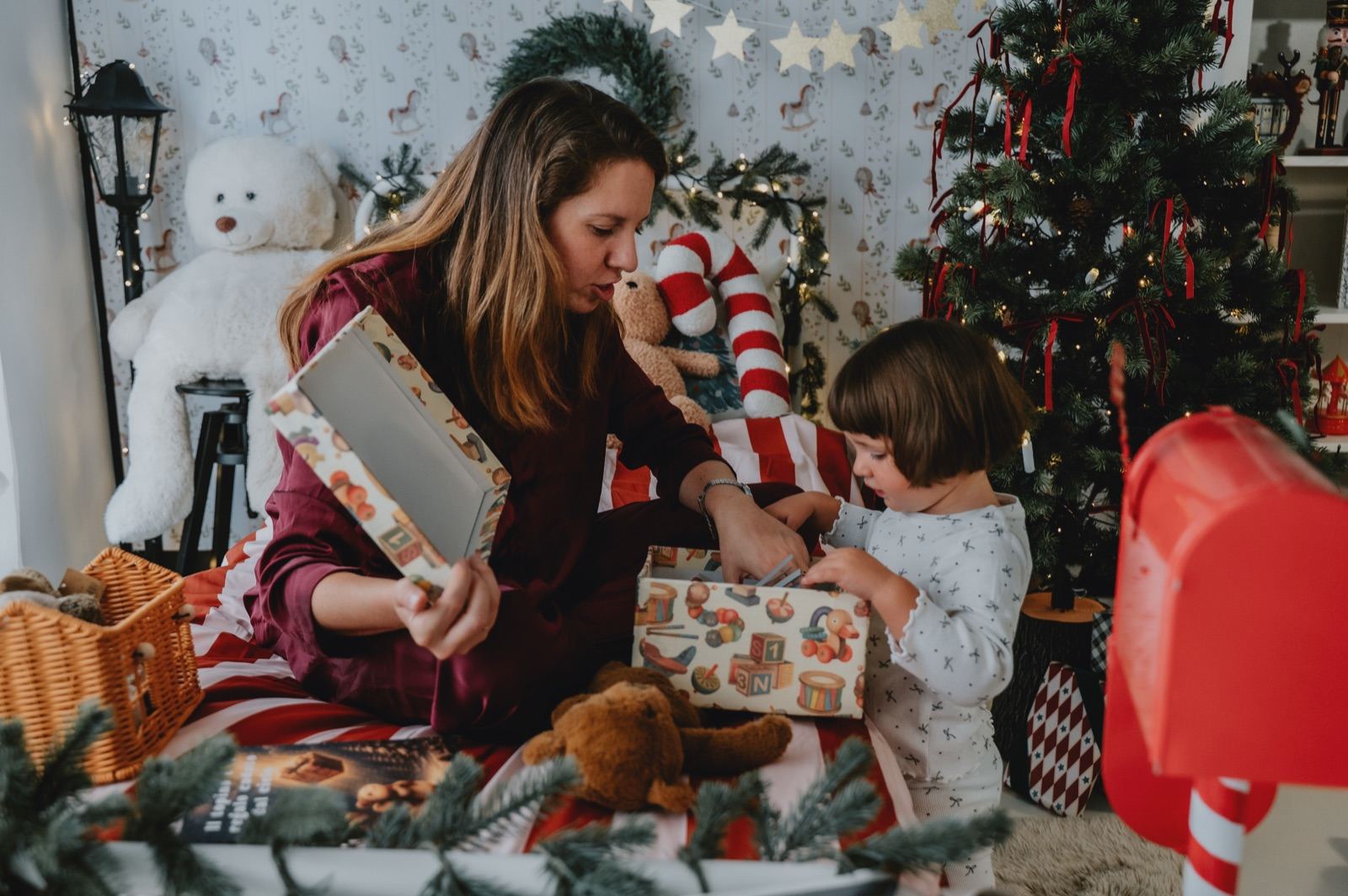 Mamma e bambina che aprono i pacchetti davanti all'albero di Natale