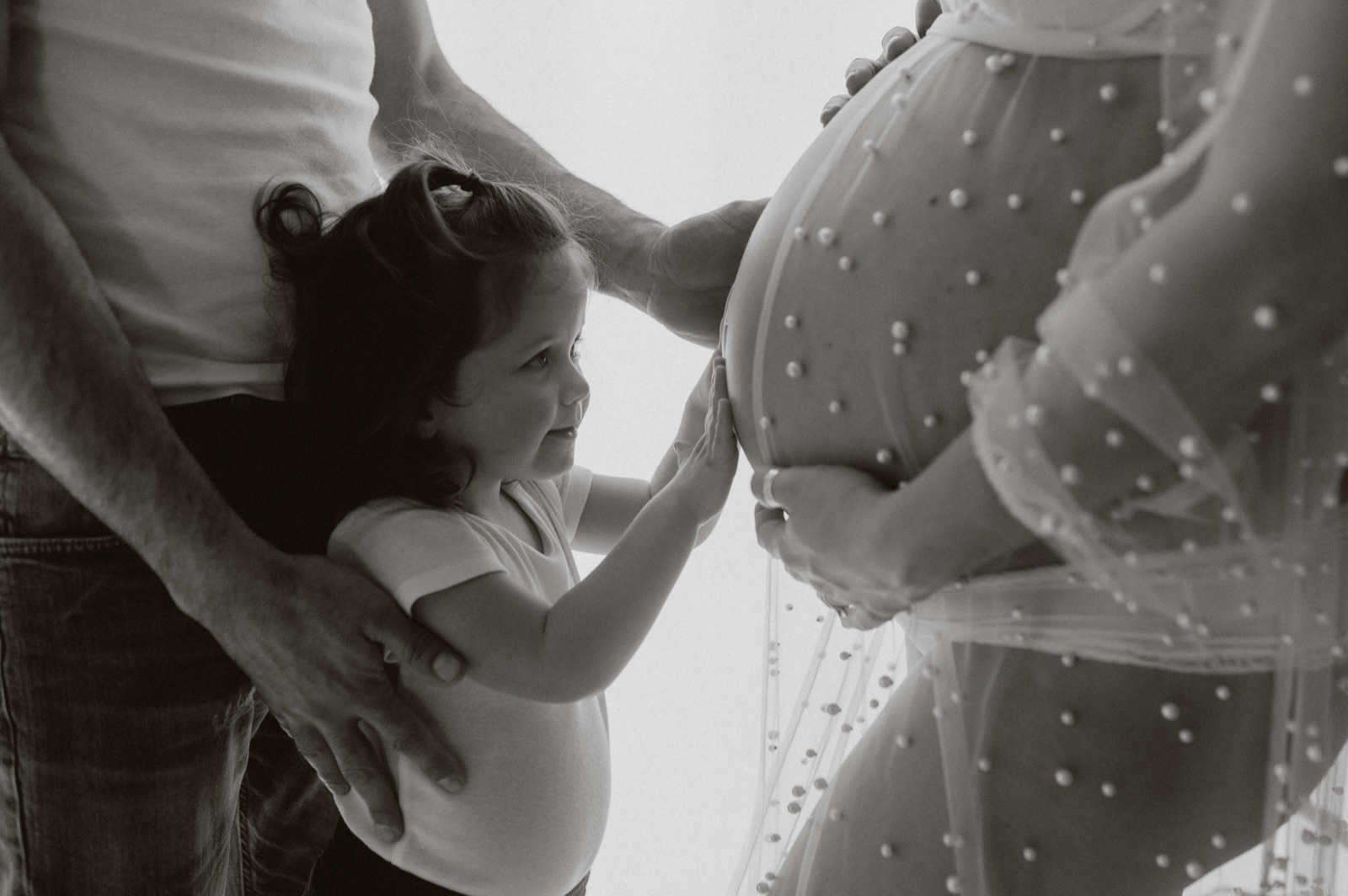 Fotografia in bianco e nero di una bambina che tocca il pancione della mamma