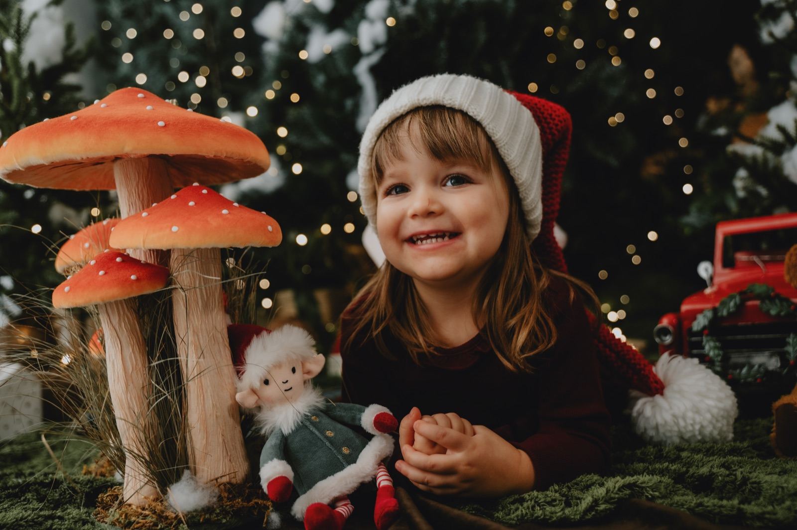 Bambina con il cappello di Babbo Natale accanto ai funghetti rossi