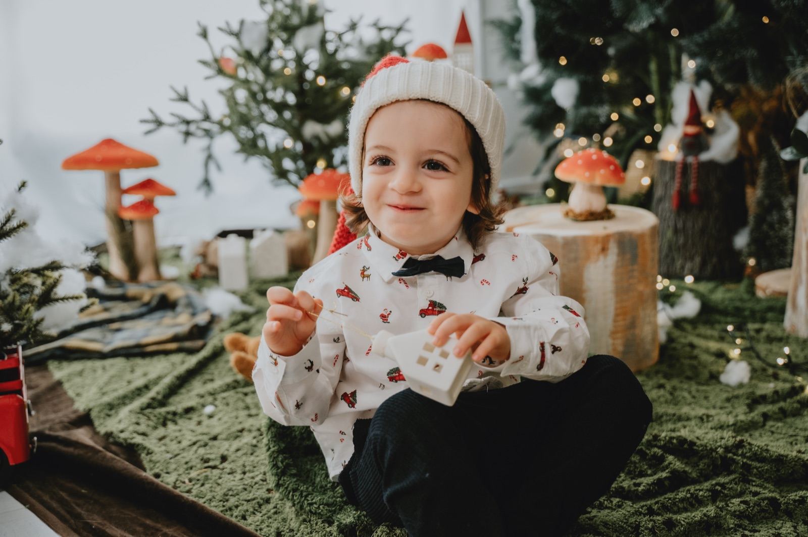 Bambino in camicia a fantasia e papillon, seduto nel set natalizio