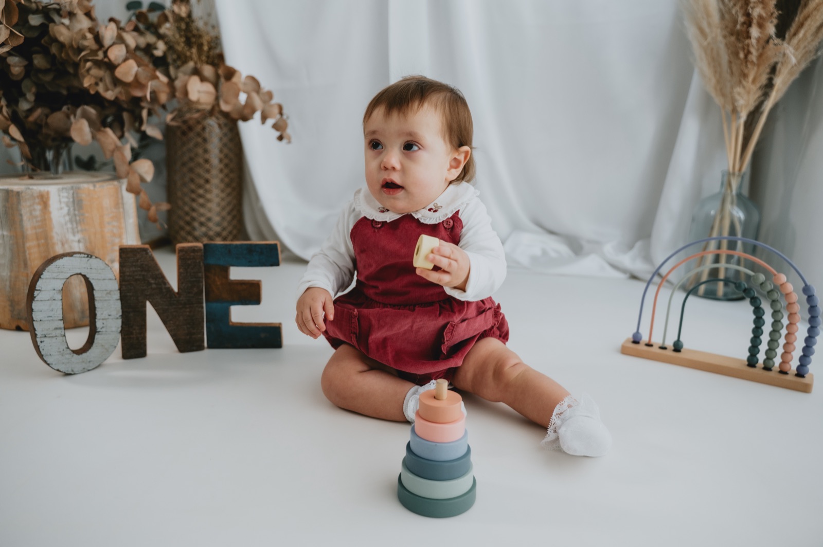 Bambina seduta accanto alle lettere ONE e a un gioco a impilare