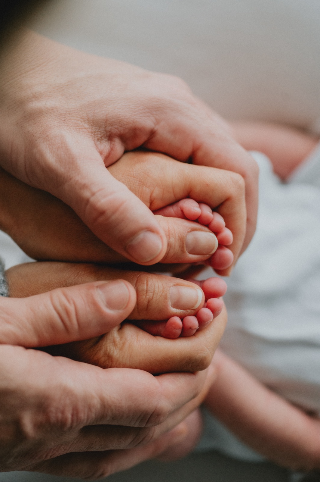 I piedini del neonato tenuti fra le mani dei genitori