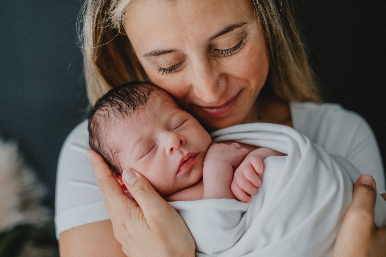 Mamma che tiene il neonato appoggiato alla guancia