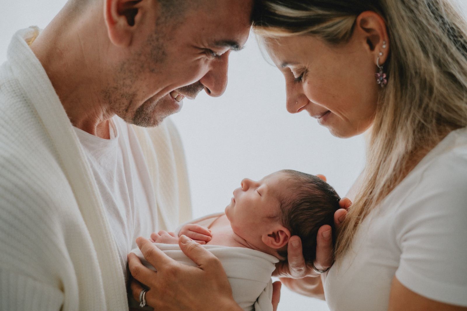 Mamma e papà che guardano il neonato tenuto fra le loro mani