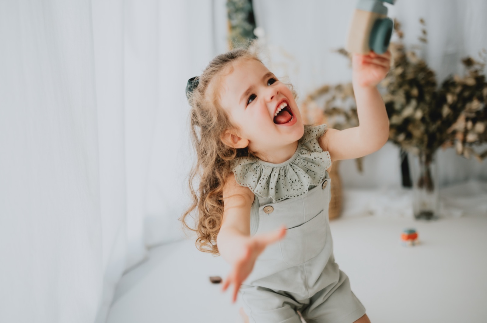 Bambina che ride e alza un gioco sopra la testa
