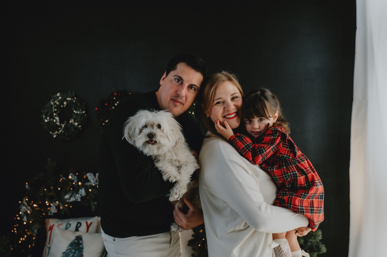Famiglia con il cane bianco che ride davanti all'albero