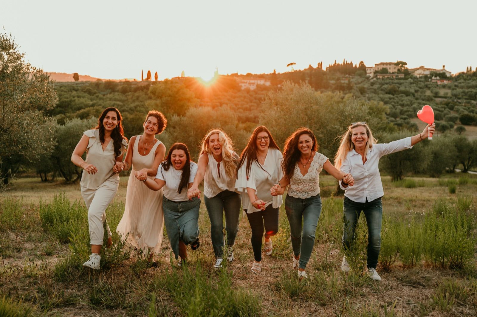 Un gruppo di amiche che corre in un campo al tramonto