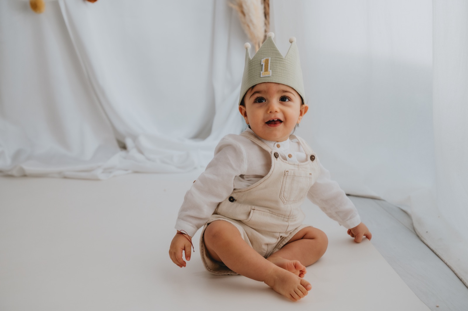 Bambino con la coroncina del primo compleanno, seduto in studio