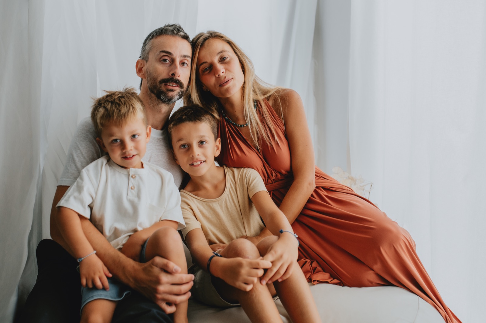 Famiglia con due bambini seduta davanti a una tenda chiara
