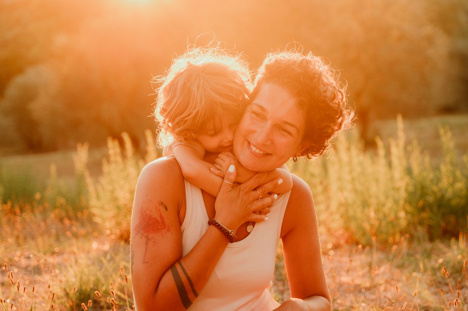 Mamma e bambino abbracciati nella luce calda del tramonto