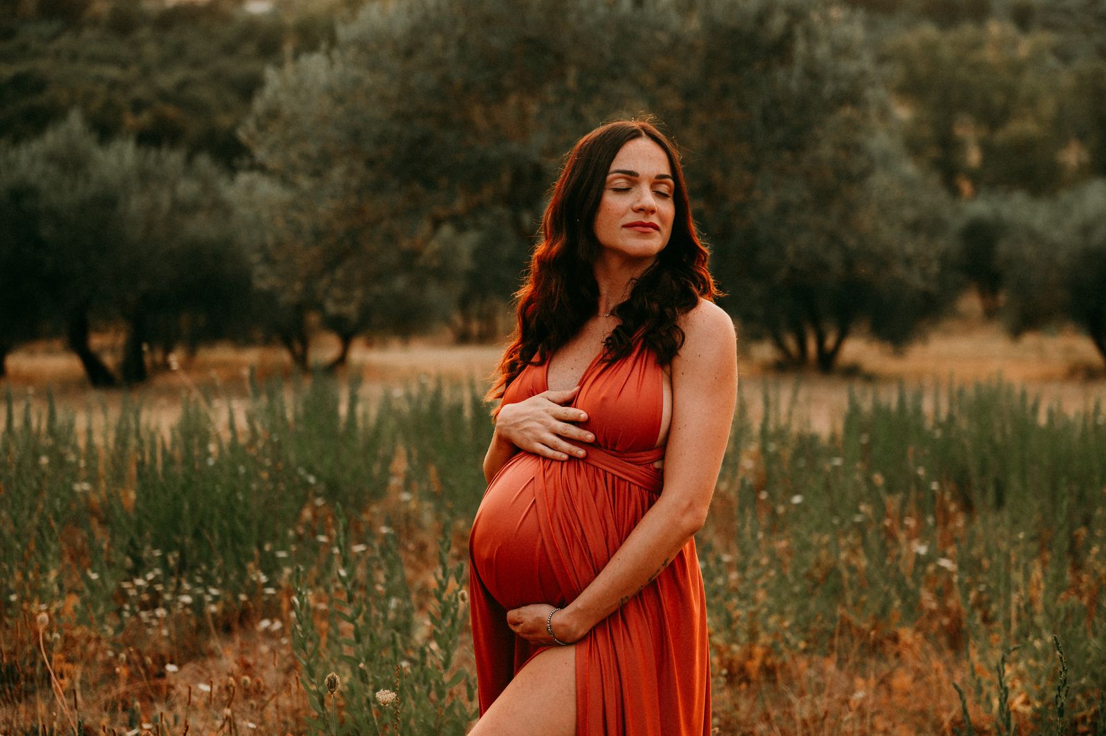 Futura mamma in abito rosso in un campo fiorito sulle colline di Firenze