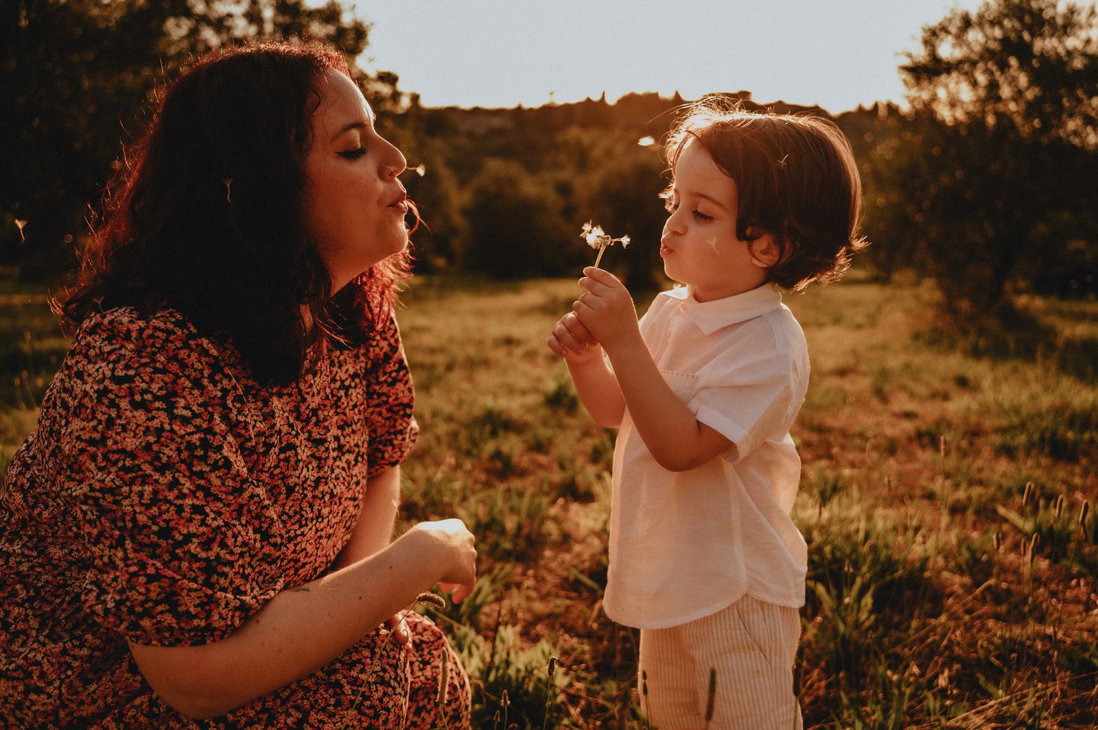Mamma e bambino che soffiano insieme un soffione