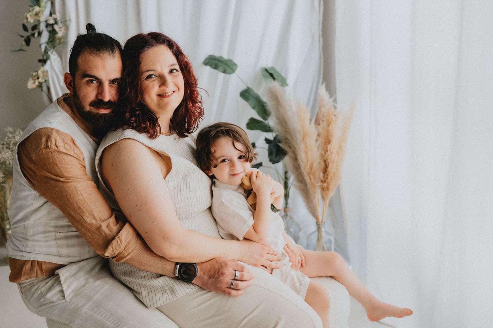 Famiglia di quattro persone seduta insieme davanti a un fondale chiaro