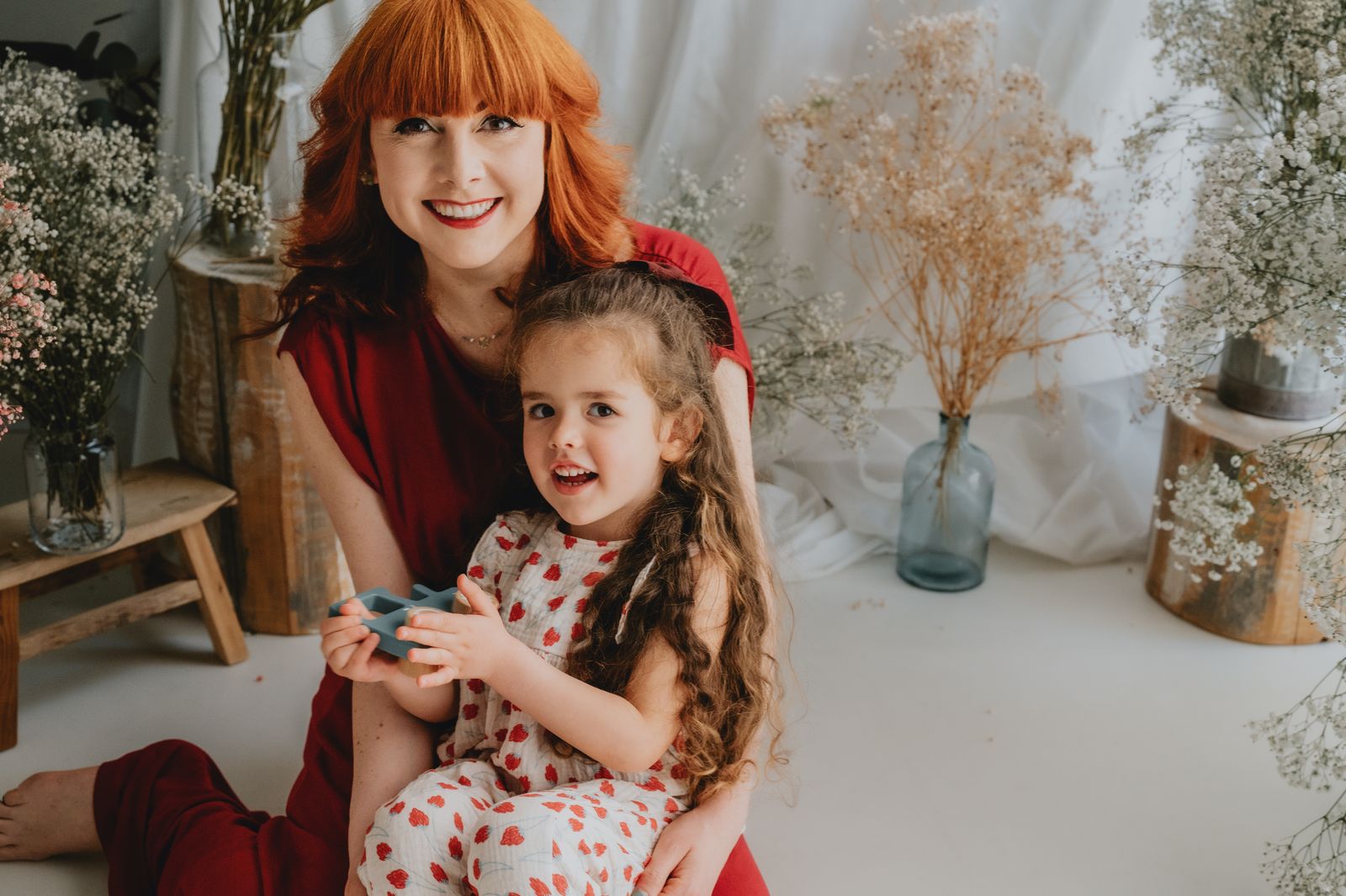 Mamma e figlia sedute a terra fra i fiori secchi dello studio