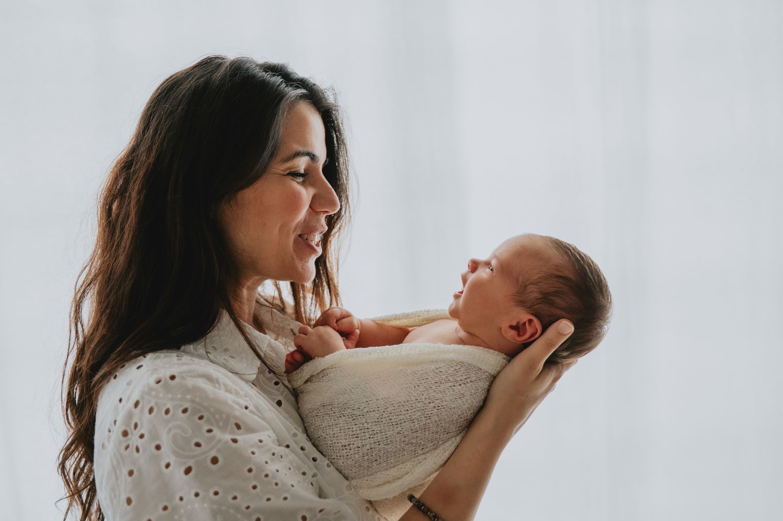 Mamma che tiene in braccio il suo neonato nello studio fotografico di Firenze