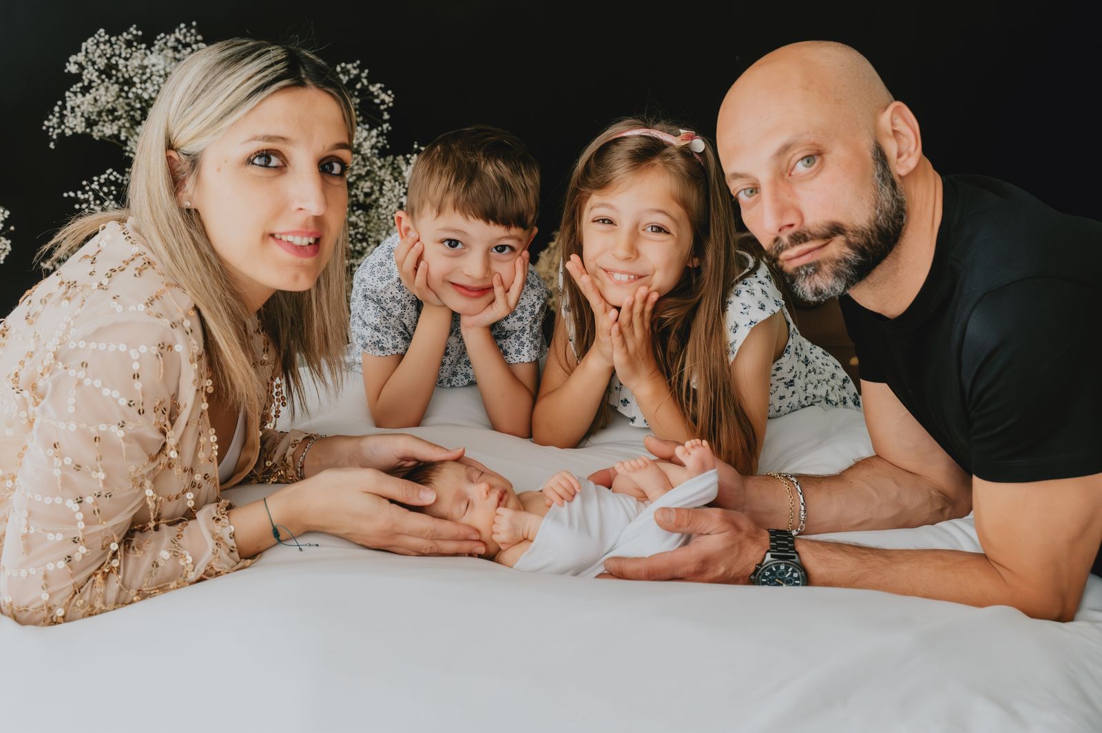Famiglia di quattro persone distesa intorno al neonato in studio