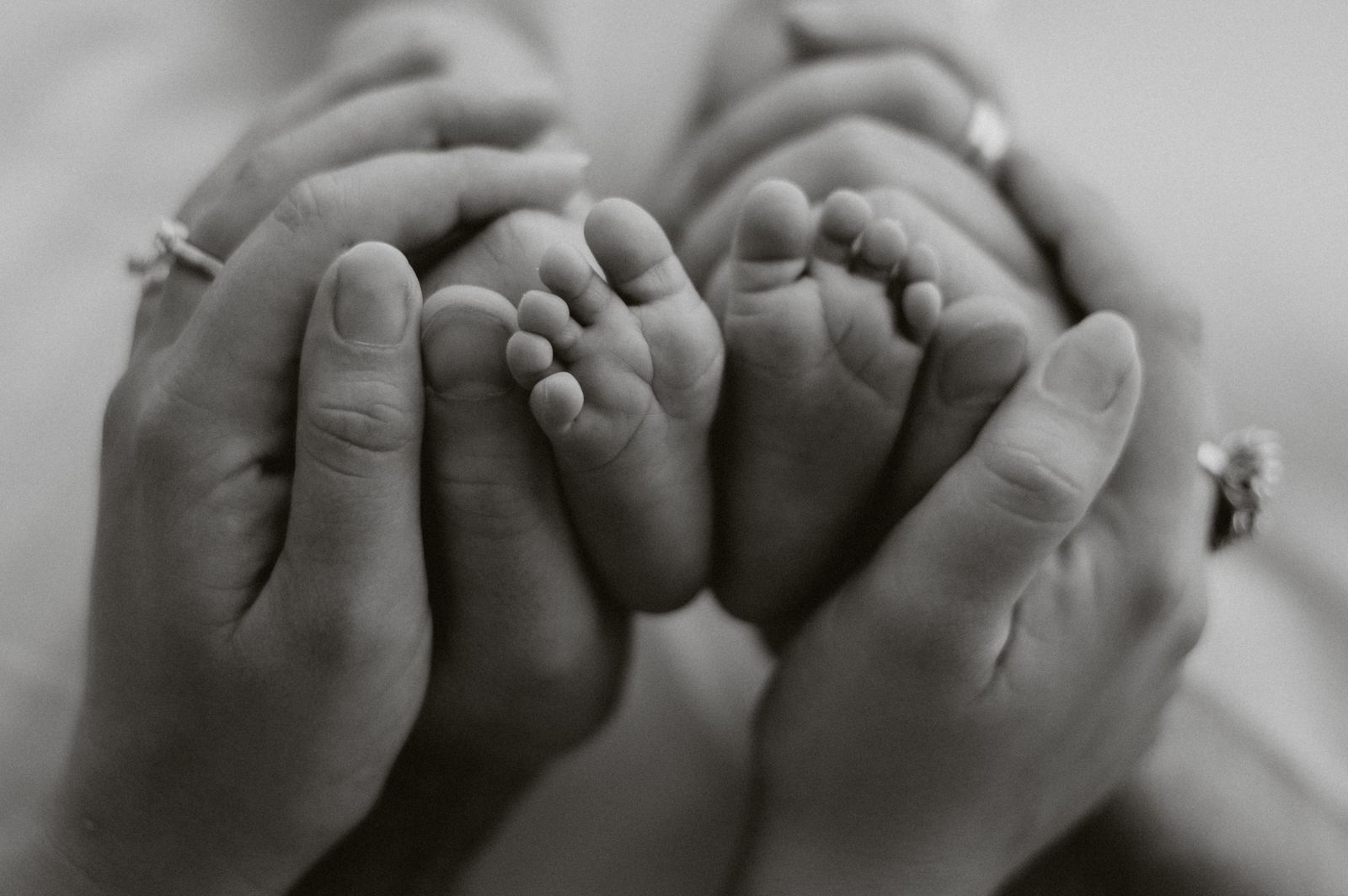 I piedini di un neonato fra le mani dei genitori, in bianco e nero