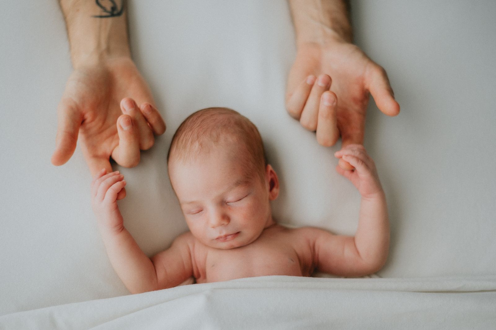 Neonato che stringe le dita dei genitori