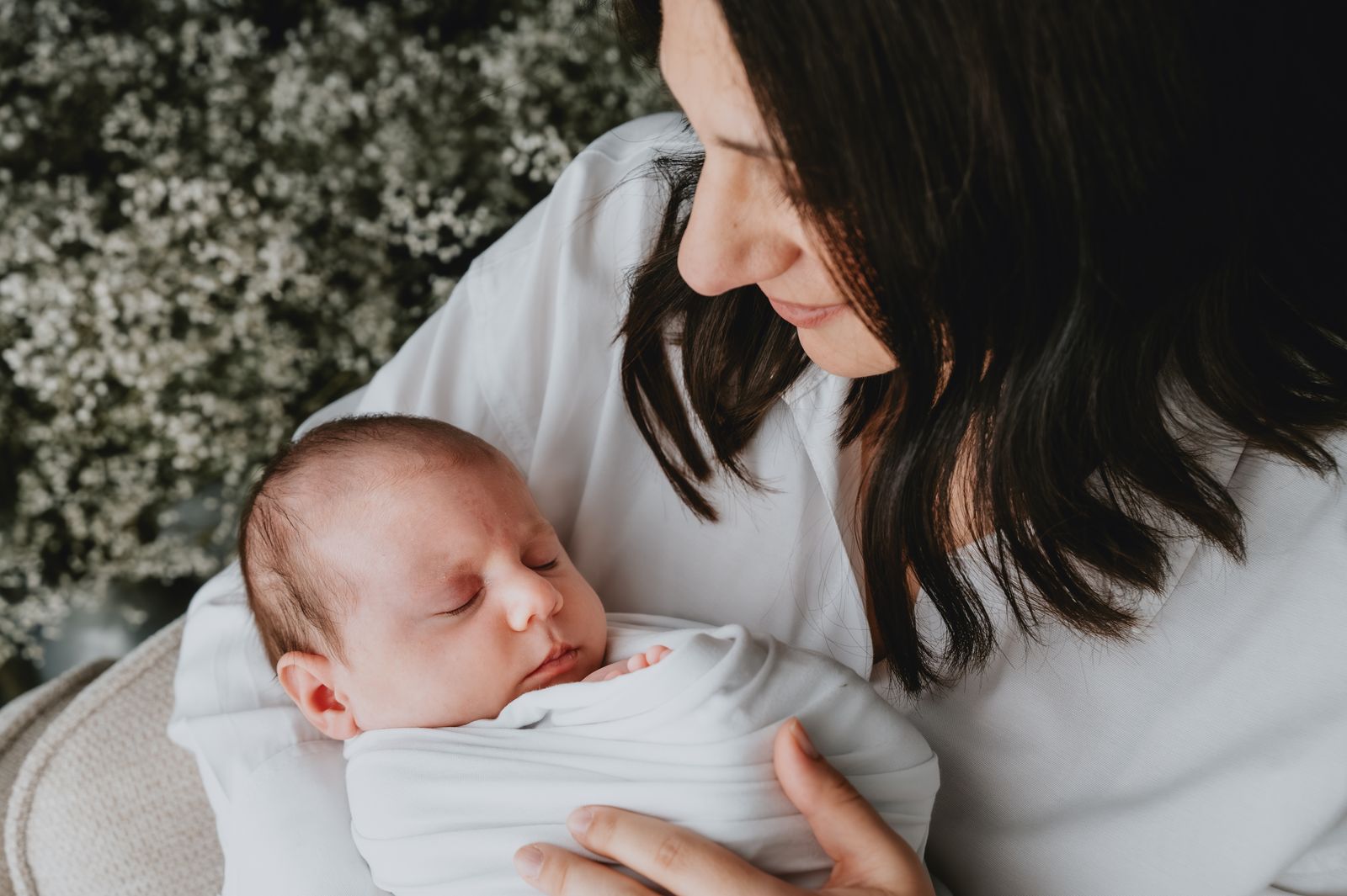 Mamma che guarda il suo neonato avvolto in un fascio bianco