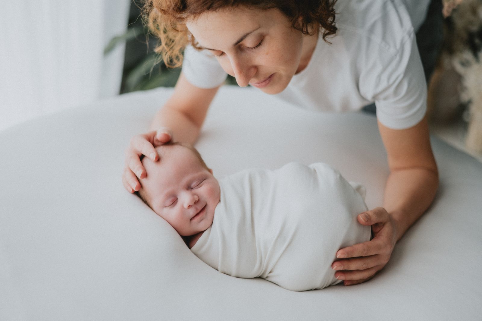 Mamma che osserva il suo neonato addormentato durante lo shooting
