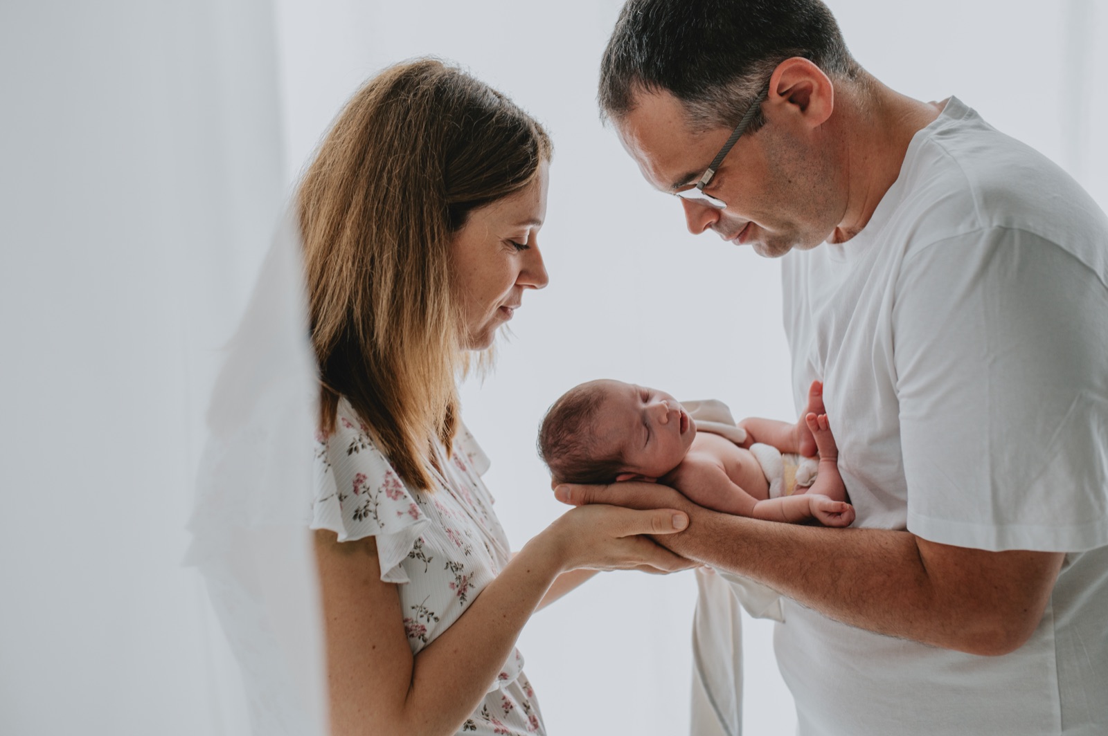 Mamma e papà che guardano il neonato tenuto fra le loro mani