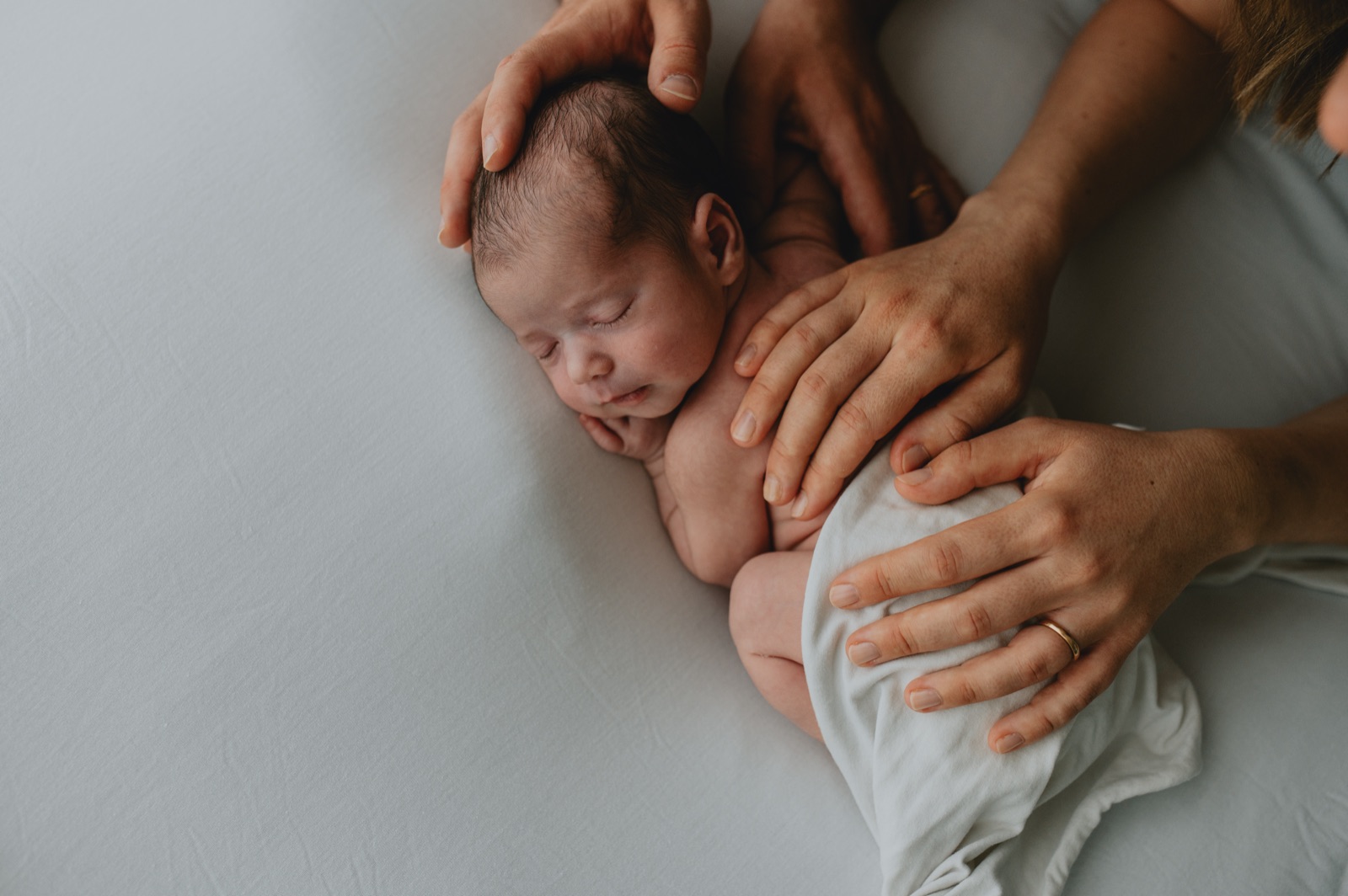 Le mani dei genitori appoggiate sul neonato addormentato