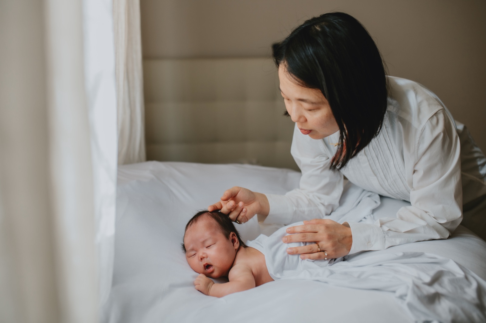 Mamma che accarezza la testa del neonato sul letto