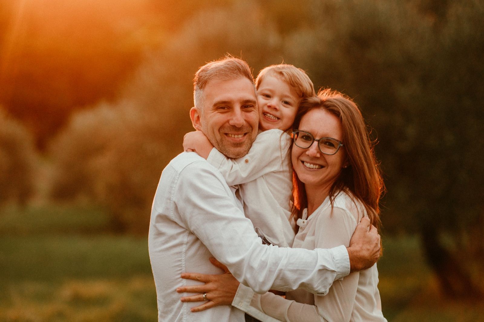 Famiglia abbracciata nella luce calda del tramonto