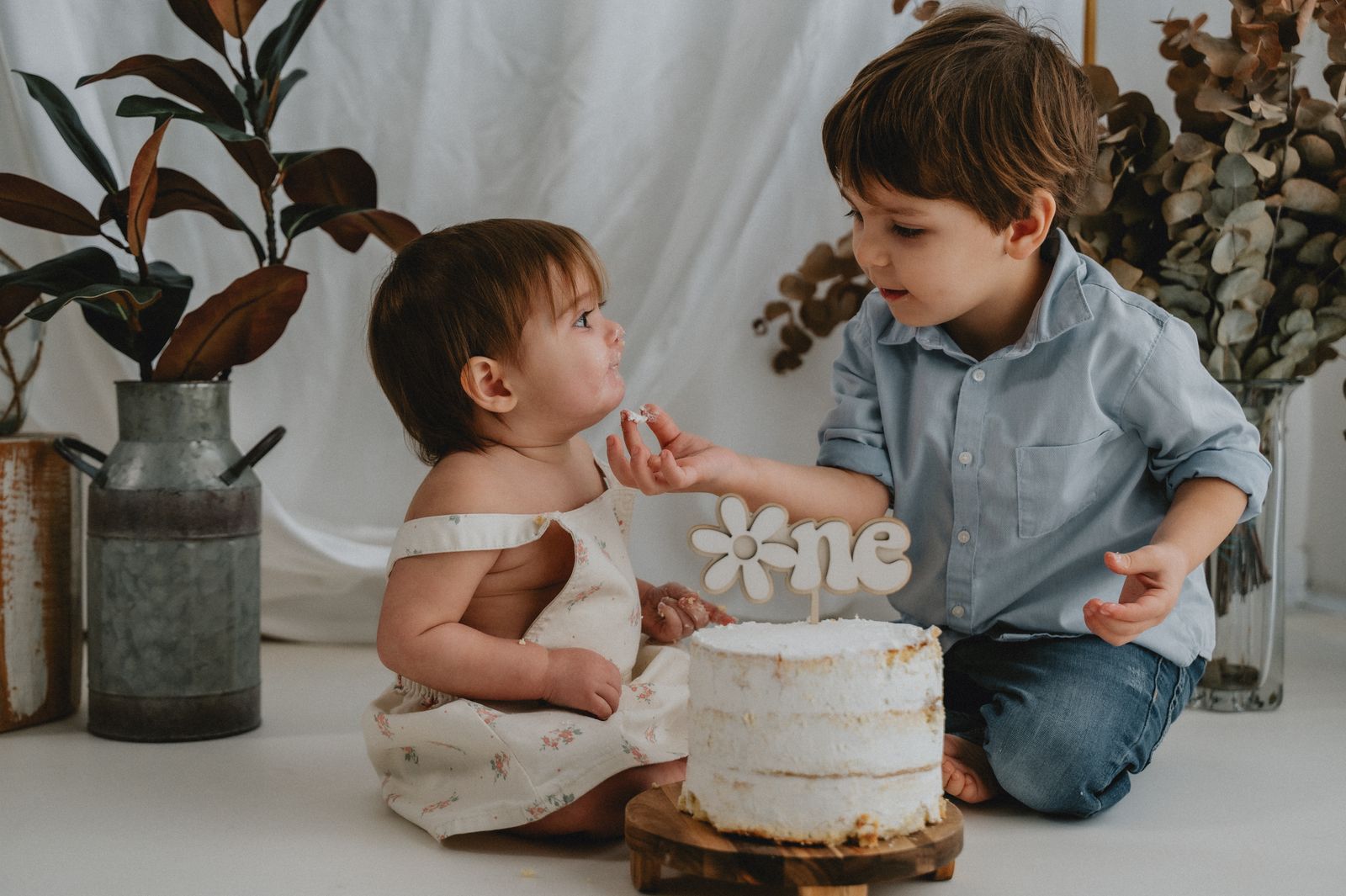 Fratello e sorella accanto alla torta del primo compleanno