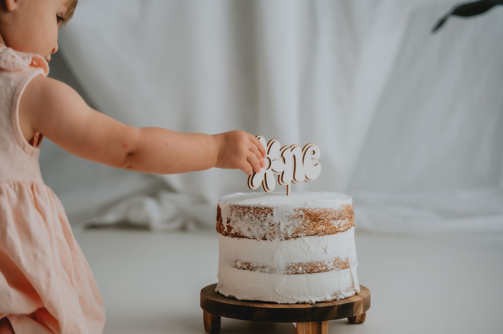 Manina che tocca il cake topper della torta del primo compleanno