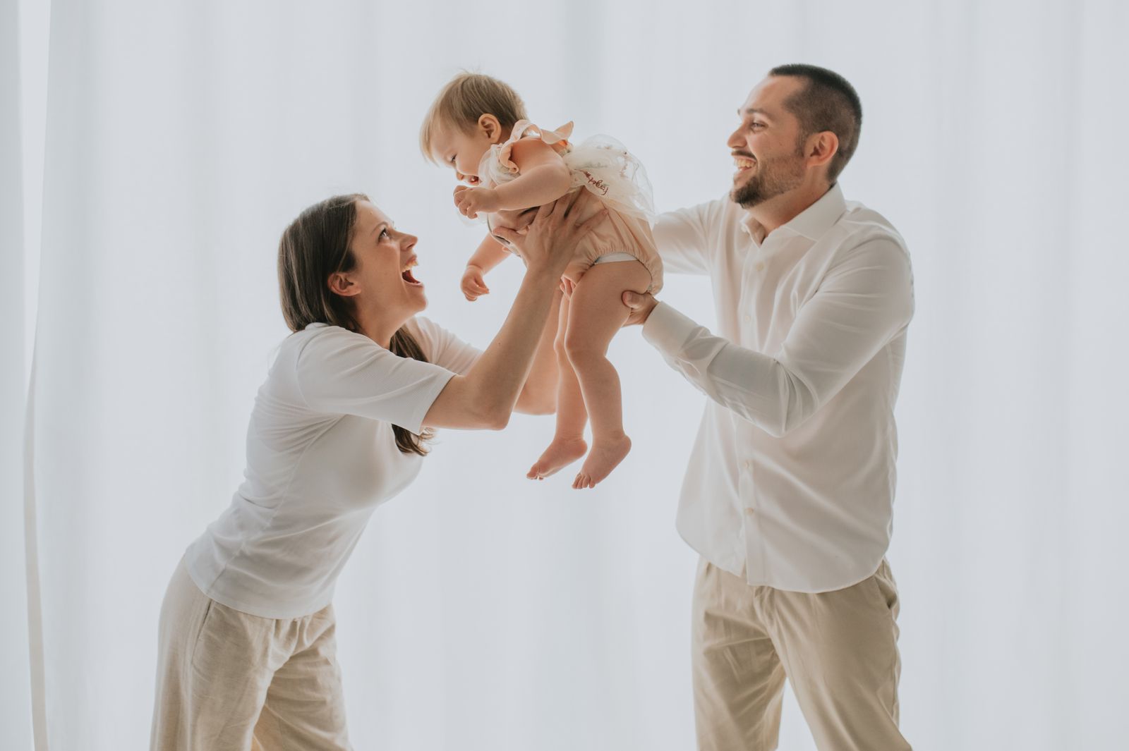 Mamma e papa' che sollevano il bambino nel giorno del primo compleanno